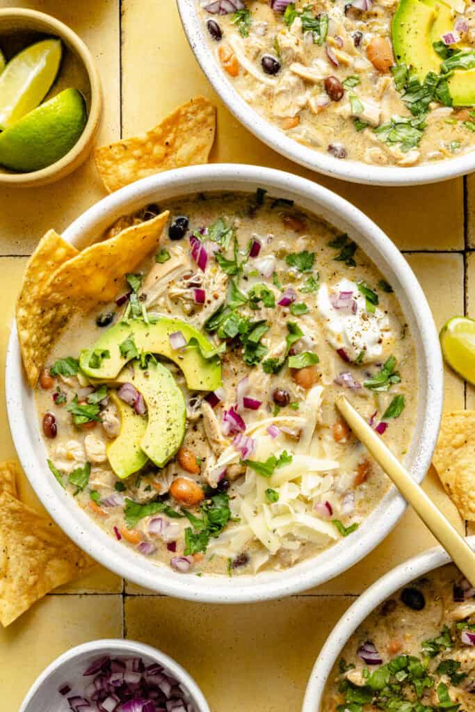 green chicken enchilada soup in a bowl with a spoon and topped with chips