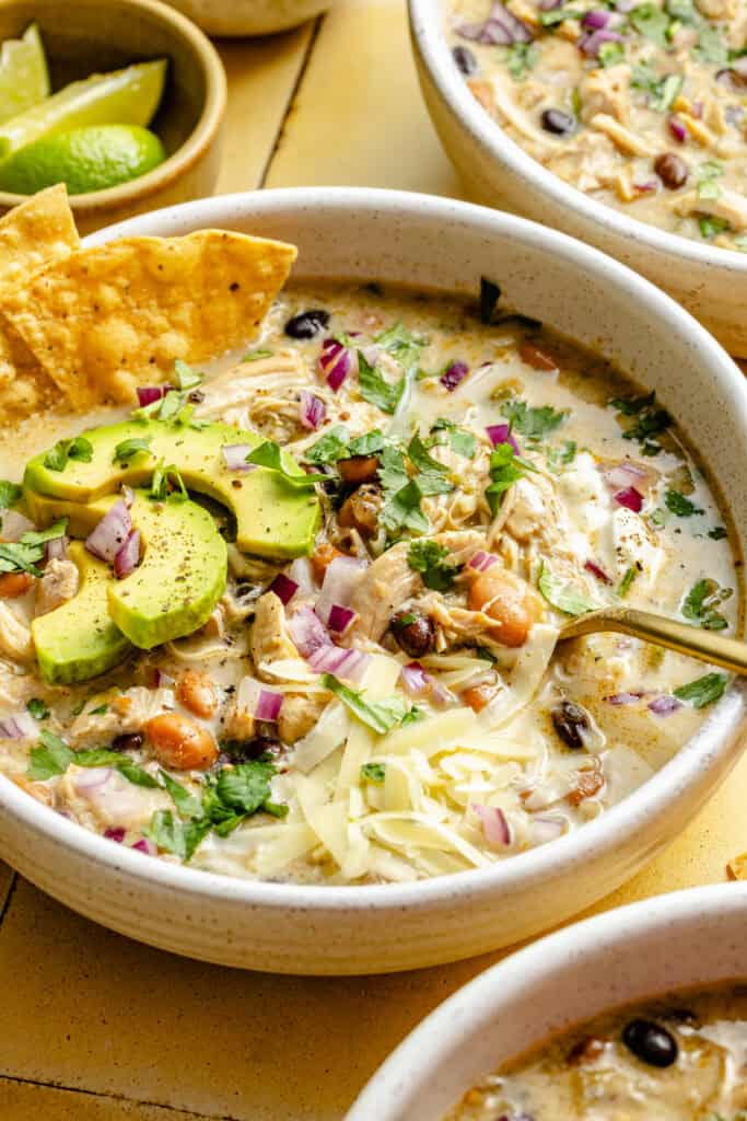 green chicken enchilada soup in a bowl with a spoon and topped with chips