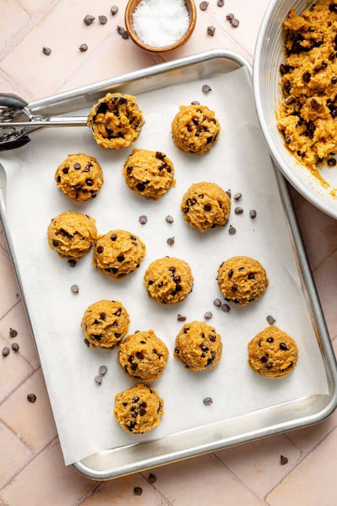 pumpkin protein balls being scooped on sheet pan