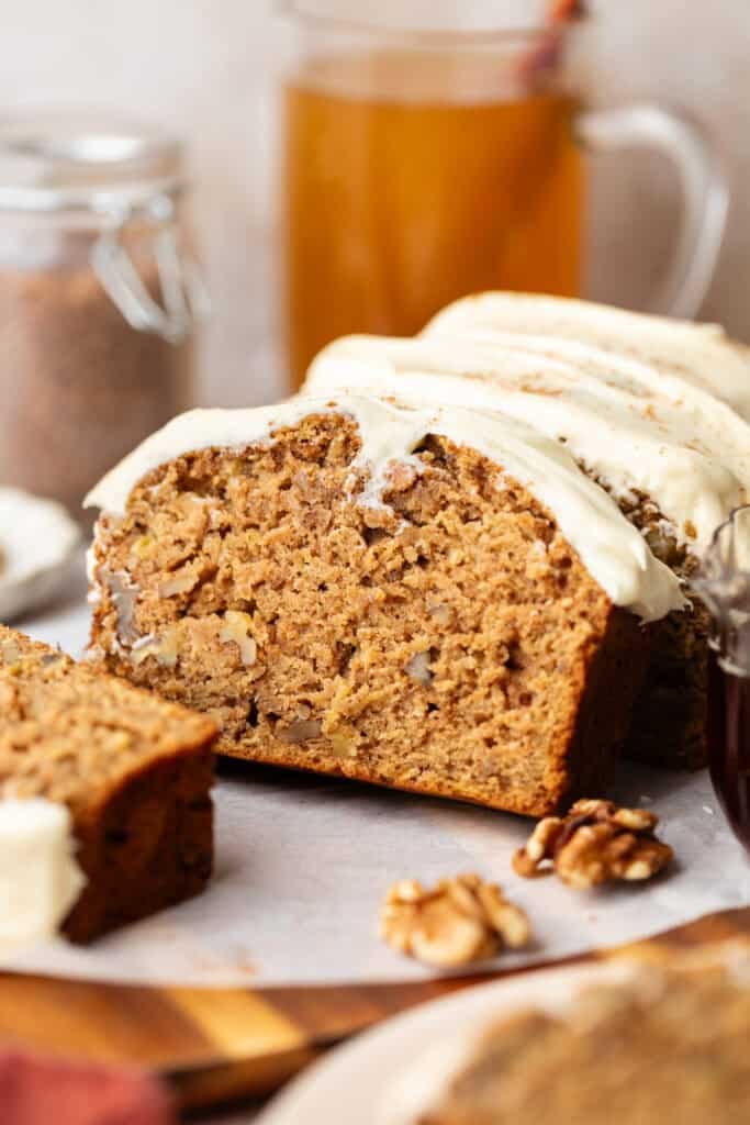 brown butter apple bread sliced and topped cream cheese frosting
