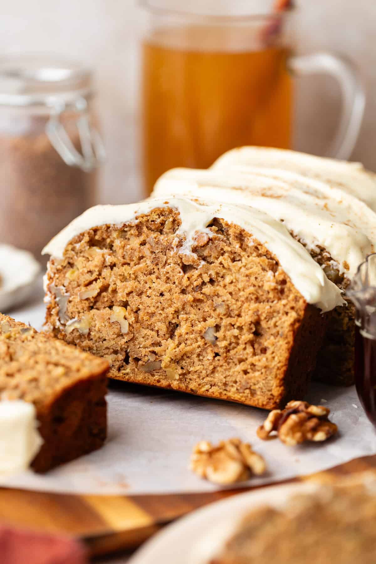 brown butter apple bread sliced and topped cream cheese frosting