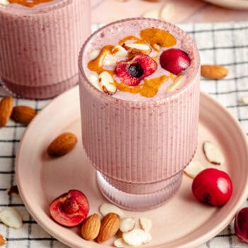 cherry almond smoothie on plate topped with cherries and sliced almonds