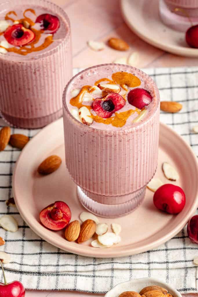 cherry almond smoothie on plate topped with cherries and sliced almonds