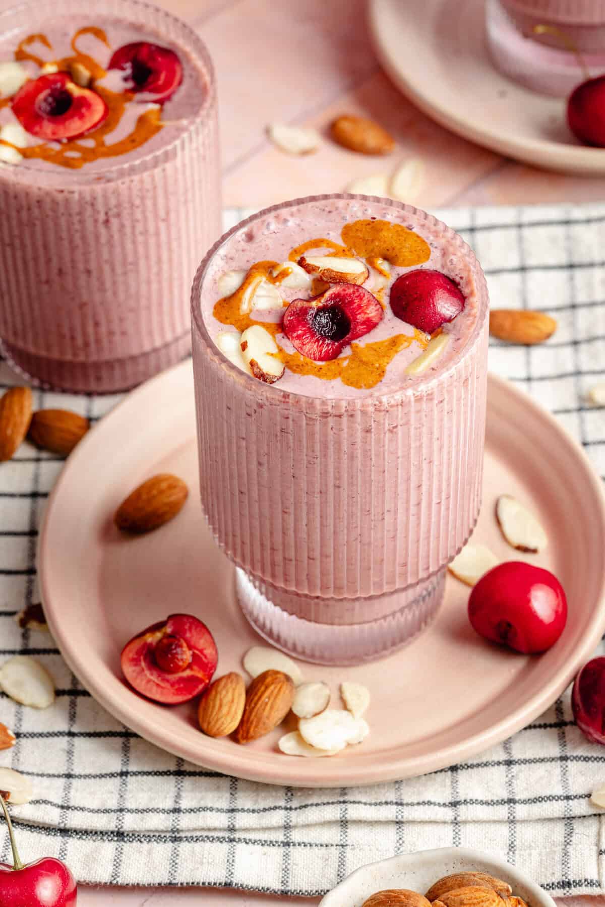 cherry almond smoothie on plate topped with cherries and sliced almonds