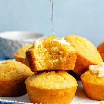 cornbread muffins stacked on each other with a drizzle of honey butter