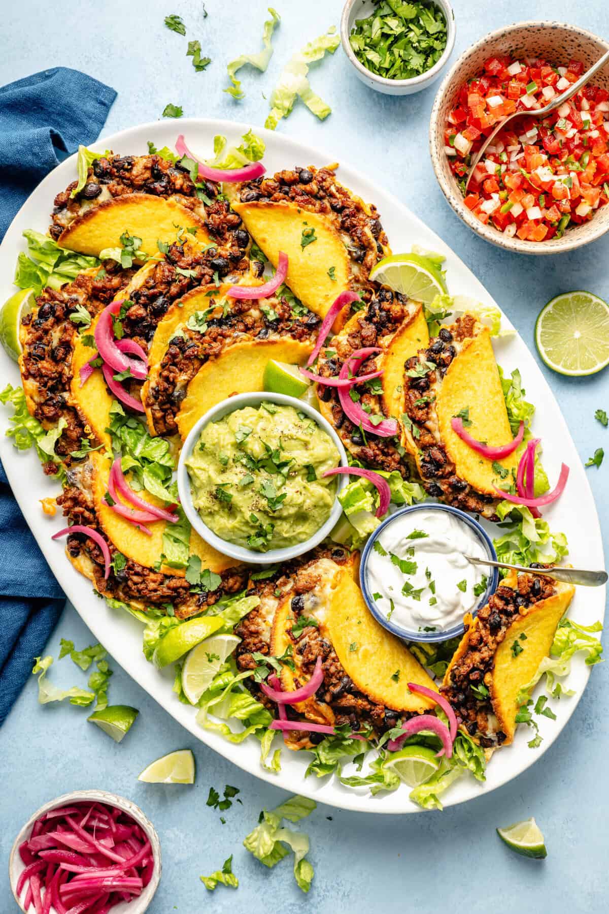 oven baked tacos on a platter with guacamole and greek yogurt
