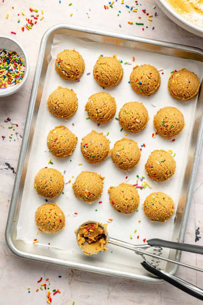 cake batter protein balls being scooped on sheet pan