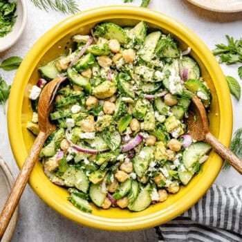 cucumber chickpea salad in mixing bowl with wooden spoons