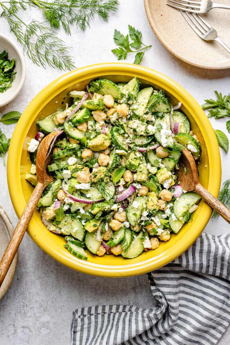 cucumber chickpea salad in mixing bowl with wooden spoons
