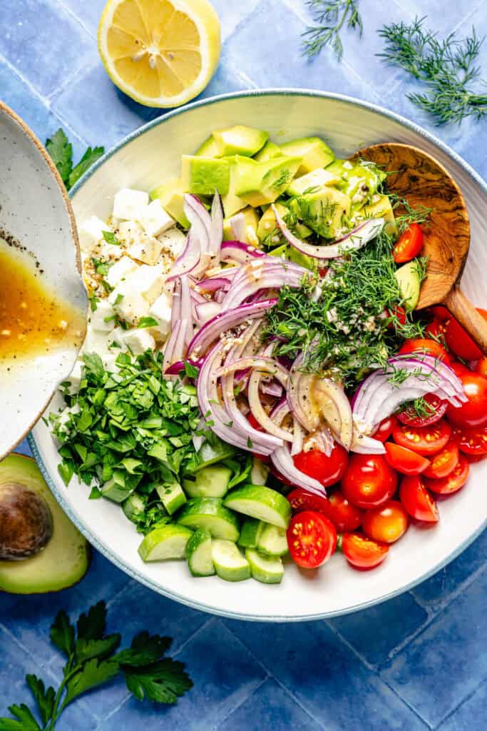 dressing being poured on a salad