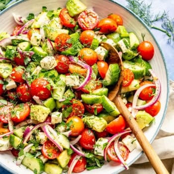 tomato cucumber avocado salad with serving spoon