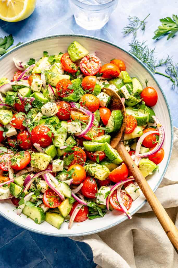 tomato cucumber avocado salad with serving spoon