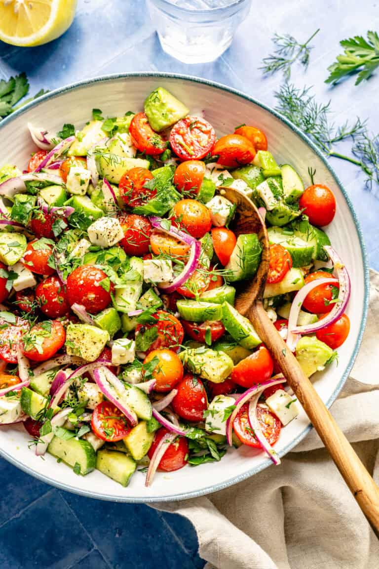 tomato cucumber avocado salad with serving spoon